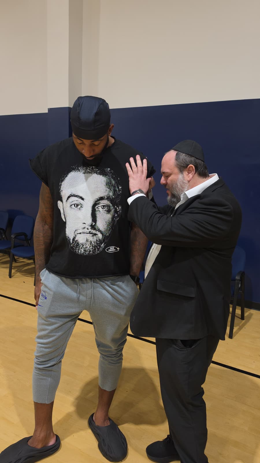 A visitor and a member of the Landow community sharing a Jewish moment in the gymnasium